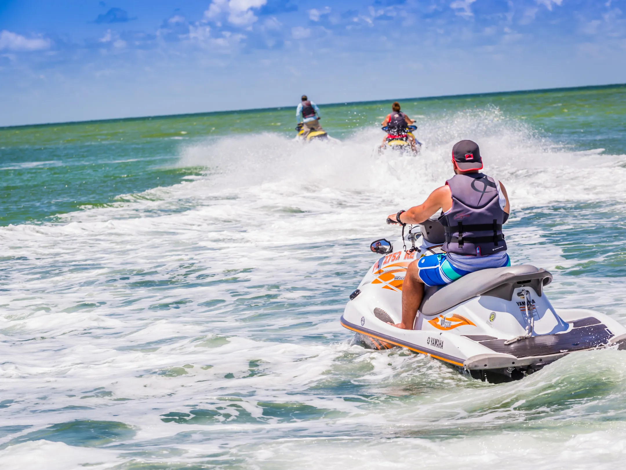 a man riding a jet ski in the water behind other jet skiers