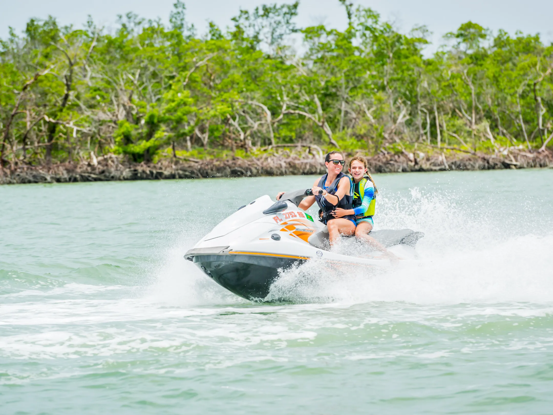a woman and child riding on a jet ski
